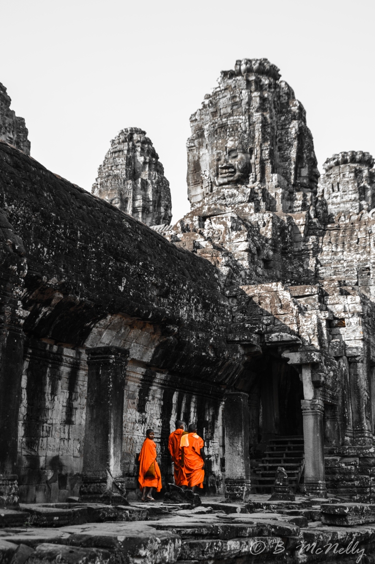 Three young monks walk through the temples of Angkor Wat.